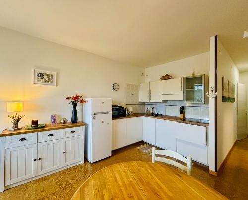 La cuisine est équipée de placards blancs et d'un réfrigérateur blanc. dans l'établissement GRADISSIMO, à Grado-Pineta
