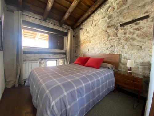 a bedroom with a bed and a stone wall at Alojamiento rural, Adrados Mar de Pinos in Adrados