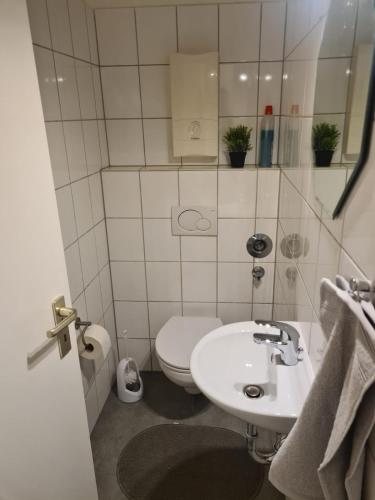 a white bathroom with a toilet and a sink at Schöne 3 Zimmer Apartment Netflix+Prime in Krefeld