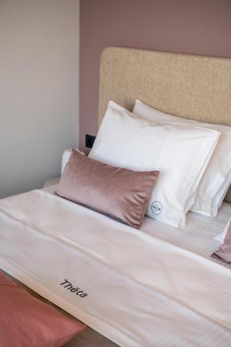 a bed with white sheets and pillows on it at Theta Boutique Hotel in Chania