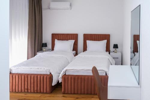 um quarto com 2 camas e lençóis brancos em Nest Apartments em Gjakove