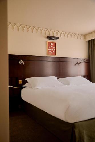 a bed in a hotel room with a clock on the wall at Grand Hotel Bellevue London in London