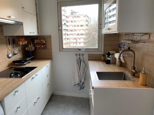 Elle comprend une petite cuisine avec un évier et une fenêtre. dans l'établissement APPARTEMENT + Parking 45m2 TOUR EIFFEL, à Paris