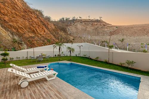 a villa with a swimming pool and a table and chairs at ELIVAAS Shourya Eden Luxe 3BHK Villa with Pvt Pool, Udaipur in Udaipur