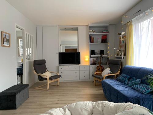 uma sala de estar com um sofá azul e cadeiras em APPARTEMENT + Parking 45m2 TOUR EIFFEL em Paris