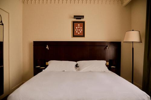 a bedroom with a large white bed and a lamp at Grand Hotel Bellevue London in London