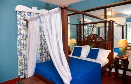 - une chambre avec un lit à baldaquin et des murs bleus dans l'établissement Casa Fontainhas, à Panaji