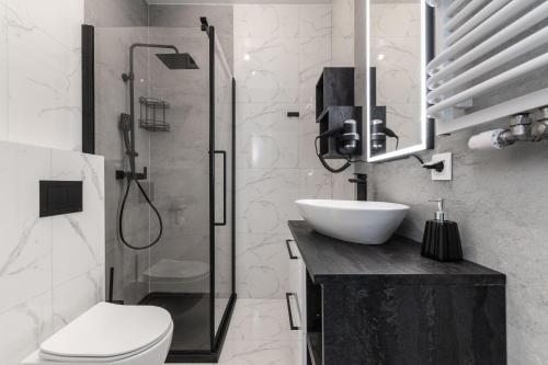 een badkamer met een douche, een toilet en een wastafel bij Doki Studio Stocznia by Grand Apartments in Gdańsk