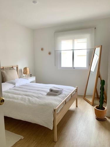 a white bedroom with a bed and a window at Cosy apartment in Almuñecar in Almuñécar