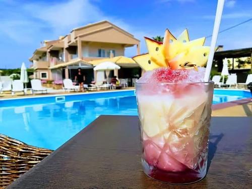a drink sitting on a table next to a pool at The Blue Sea Hotel in Agios Georgios