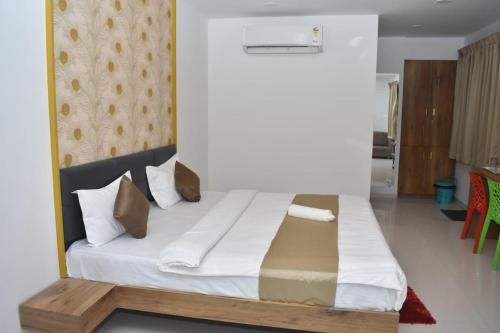 um quarto com uma cama com lençóis brancos e almofadas em Hotel Karan International ,Aurangabad em Aurangabad