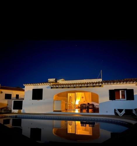 a white house with a swimming pool at night at Villa Coral in Cala'n Porter