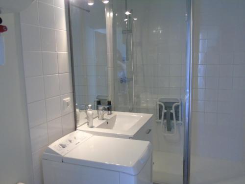 une salle de bain blanche avec un lavabo et une douche dans l'établissement Le Voilier, à Saint-Jean-de-Monts