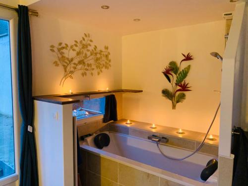 La salle de bains est pourvue d'une baignoire avec des lumières sur le mur. dans l'établissement Maisonnette cosy bord de Seine 30min paris, à Carrières-sous-Poissy