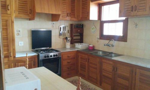 a kitchen with wooden cabinets and a stove and a sink at Casa los Cactus in Playa Migjorn