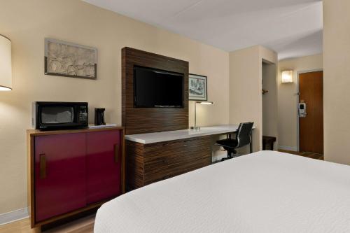 a hotel room with a bed and a desk and a tv at Ramada by Wyndham Harrisburg/Hershey Area in Harrisburg