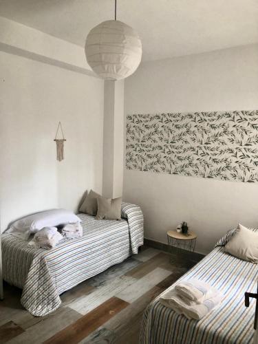 a bedroom with two beds and a pendant light at Céntrico Rota Beach. in Rota