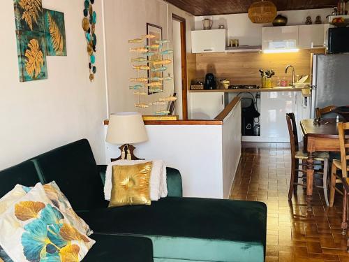 uma sala de estar com um sofá verde e uma cozinha em À casetta em Albertacce