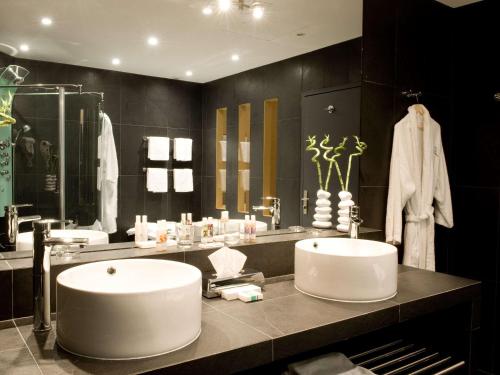 La salle de bains est pourvue d'un lavabo et d'un grand miroir. dans l'établissement Mercure Bordeaux Chateau Chartrons, à Bordeaux
