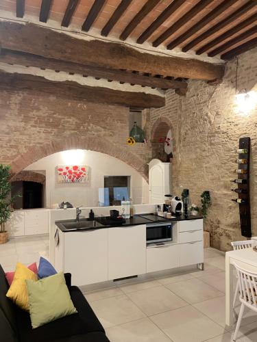 eine Küche mit weißen Schränken und einer Steinmauer in der Unterkunft I Fiori di Colle, l’anima Toscana “Loft” in Colle di Val d’Elsa