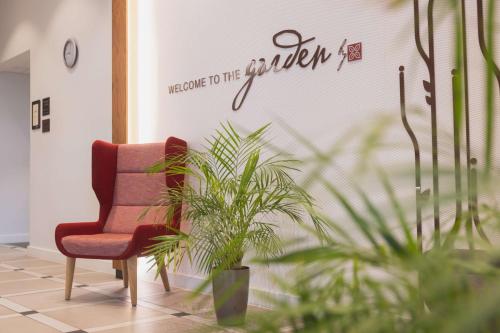 a red chair and a plant in a hallway at Hilton Garden Inn Birmingham Airport Uk in Bickenhill