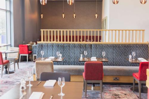 a dining room with tables and red chairs at Hilton Garden Inn Birmingham Airport Uk in Bickenhill