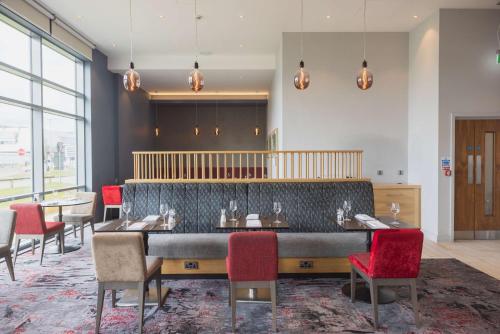 a dining room with a large table and red chairs at Hilton Garden Inn Birmingham Airport Uk in Bickenhill