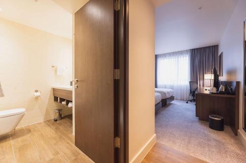 a hotel room with a bathroom with a toilet and a sink at Hilton Garden Inn Birmingham Airport Uk in Bickenhill