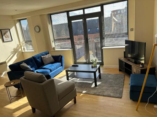een woonkamer met een blauwe bank en een tv bij Modern 2 BDR Flat in Nottingham City Centre with free parking in Nottingham