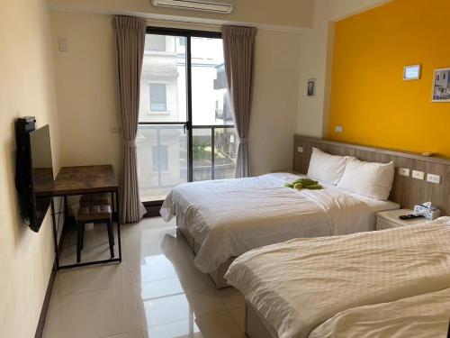 a hotel room with two beds and a window at 羅東旅行家民宿 in Luodong