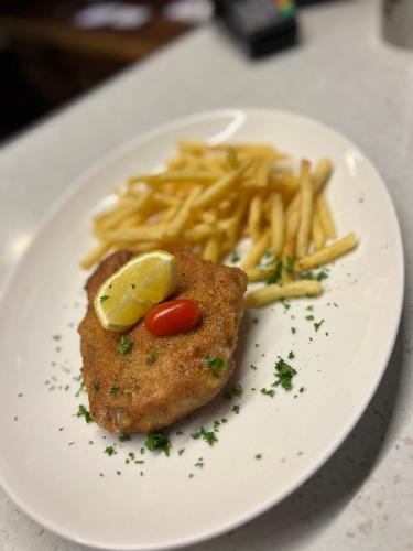 a white plate with a piece of fish and french fries at Landgasthof Hotel Rebstock in Stühlingen