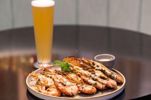a plate of shrimp on a table with a glass of beer at Hilton Garden Inn Umhlanga Arch in Durban