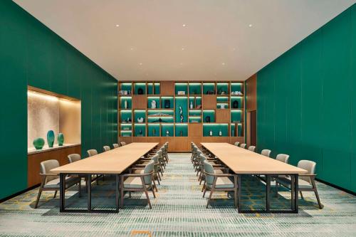 a conference room with green walls and tables and chairs at Hilton Garden Inn Suzhou Wuzhong in Suzhou