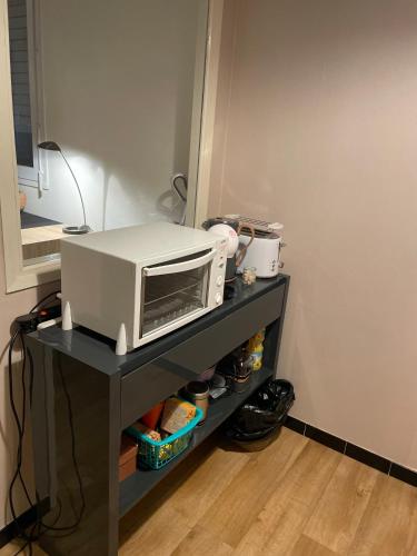 un four micro-ondes sur une étagère noire dans une cuisine dans l'établissement Manuezen studio très fonctionnel au calme, à Vesoul