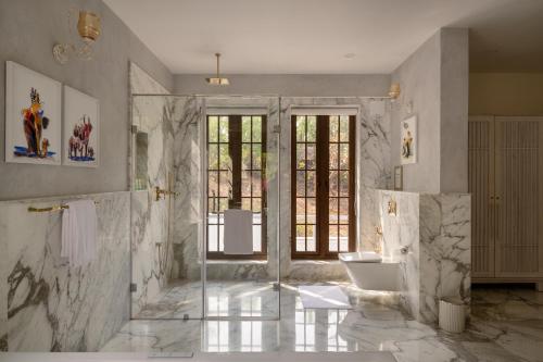 a bathroom with two sinks and a shower with marble walls at Melhor stays Villas - UL- C2 7BHK villa with private pool, Assagao in Assagao