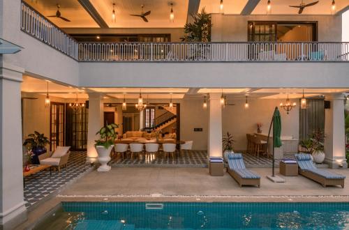 an indoor swimming pool with chairs and a house at Melhor stays Villas - UL- C2 7BHK villa with private pool, Assagao in Assagao