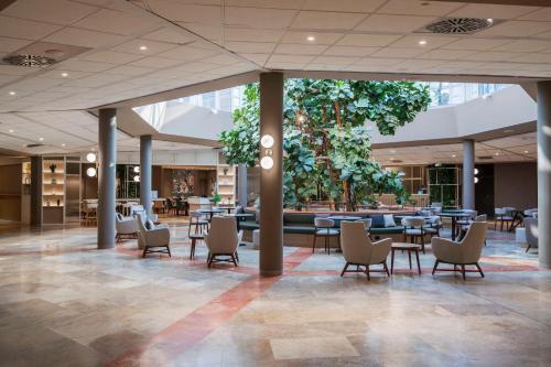 a lobby with tables and chairs in a building at Hilton Garden Inn Bologna North in Bologna