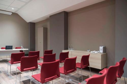 a waiting room with red chairs and a desk at Hilton Garden Inn Bologna North in Bologna