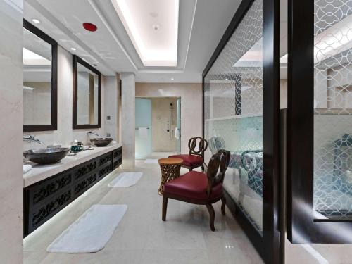 Rixos Marina Abu Dhabi في أبوظبي: حمام مع حوض وغطاء مع كرسيين