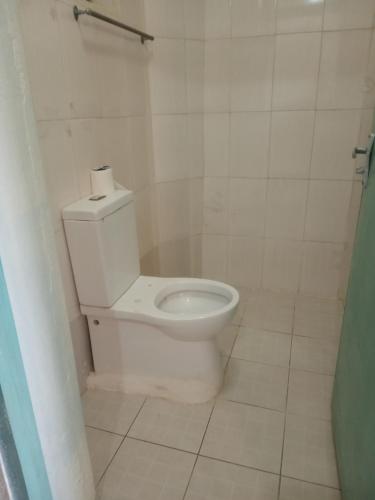 a bathroom with a toilet and a tiled floor at Tamara Studio Apartment in Shanzu in Mtwapa