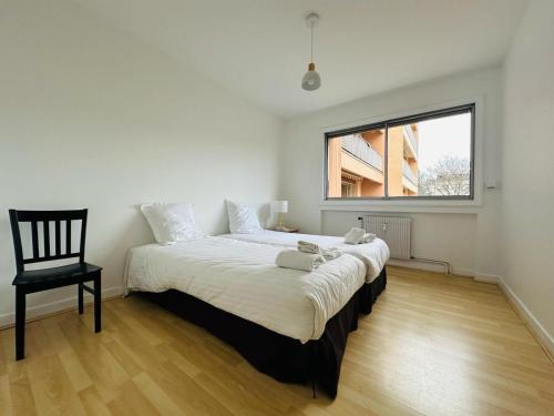 - une chambre blanche avec un grand lit et une chaise dans l'établissement Hotel Chris'tel, au Puy-en-Velay