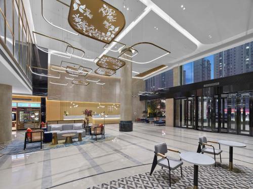 a lobby with tables and chairs in a building at Hilton Garden Inn Anshan Haicheng in Anshan