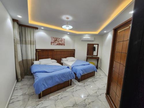 - une chambre avec 2 lits et des couettes bleues dans l'établissement Porto said بورتوسعيد غرفتين وصاله, à Port-Saïd