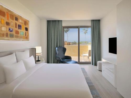a hotel room with a large bed and a chair at Mövenpick Hotel & Apartments Ghala Muscat in Muscat