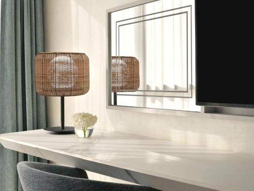 a room with a table with two lamps and a mirror at Mövenpick Hotel & Apartments Ghala Muscat in Muscat