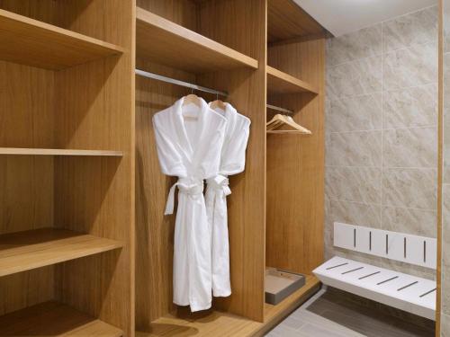 a closet with a robe hanging in it at Mövenpick Hotel & Apartments Ghala Muscat in Muscat