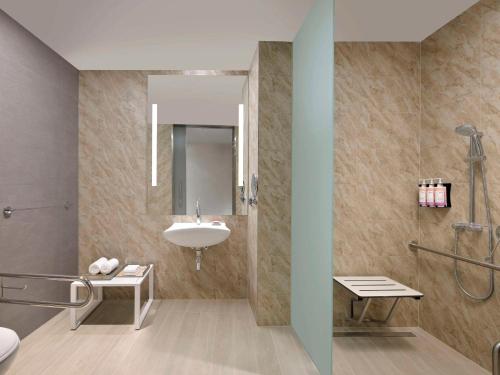 a bathroom with a sink and a shower at Mövenpick Hotel & Apartments Ghala Muscat in Muscat