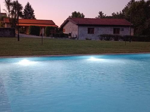 a blue swimming pool in front of a house at Rilhadas Casas de Campo in Fafe