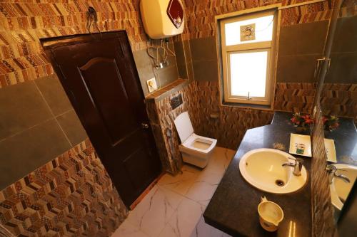 een badkamer met een wastafel, een toilet en een raam bij Vagmi Inn in Gurgaon