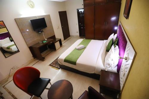 um quarto com uma cama grande e uma cadeira vermelha em Vagmi Inn em Gurgaon